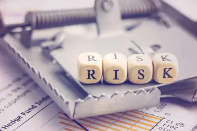 Mausefalle auf einem Tisch mit Holzwüfeln und den Buchstaben R I S K für Risk.