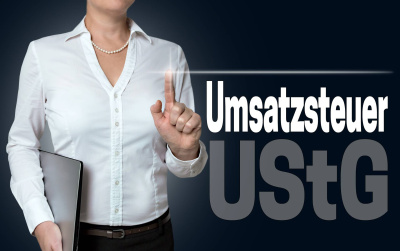 Eine weibliche Person tippt auf einen Touchscreen, auf dem der Begriff Umsatzsteuer UStG steht