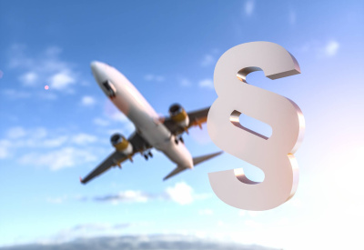Flugzeug im Hintergrund und blauem Himmel mit Wolken, davor ein Paragraphen Symbol