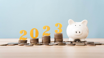 Vier Münzstapel in aufsteigender Reihenfolge mit der Jahreszahl 2023 und einem Sparschwein auf der rechten Seite.