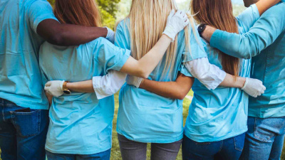 Rückansicht von einer Gruppe, die blaue T-Shirts und Einmalhandschuhe tragen.