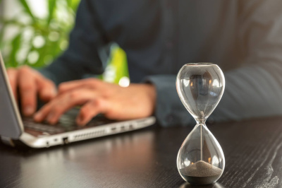 Stundenglas mit auslaufender Bürozeit als Symbol für Zeitdruck am Arbeitsplatz