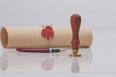 Pergamentrolle mit Wachssiegel und Siegelstempel und einem Füllfederhalter.