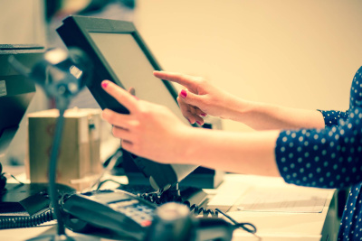 Junge Frau erledigt den Zahlungsvorgang per Hand an einer Touchscreen-Registrierkasse