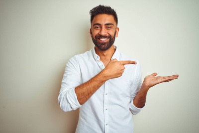 Junger Mann mit Hemd lächelt und zeigt mit der Hand und dem Finger zur Seite.