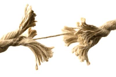 Nahaufnahme eines dicken zerrissenen Seils, das nur noch durch einen einzelnen Strang zusammengehalten wird
