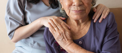 Freundliche Beziehung zwischen Betreuerin und glücklicher älterer Frau während der Pflege zu Hause.