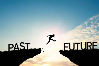 Ein Mensch springt über einen Abgrund von Past zu Future.