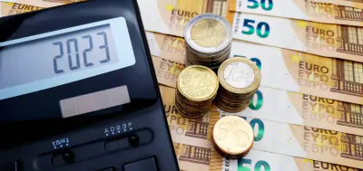 Taschenrechner und viele Euro-Münzen auf dem Hintergrund von Banknoten von 50 Euro