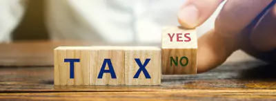 Holzblöcke mit dem Wort Steuern bzw Tax, ja oder nein.