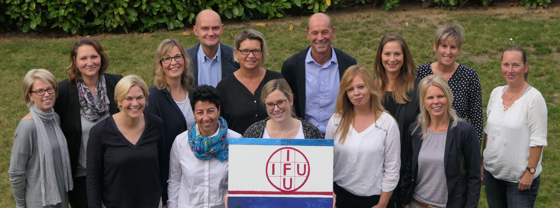 Das Team des IFU-Instituts steht um das Logo herum versammelt