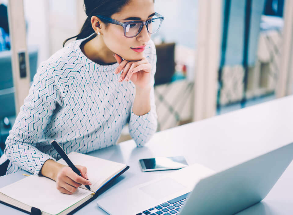 Junge Frau sitzt vor einem Laptop und belegt eien E-Learning-Seminar